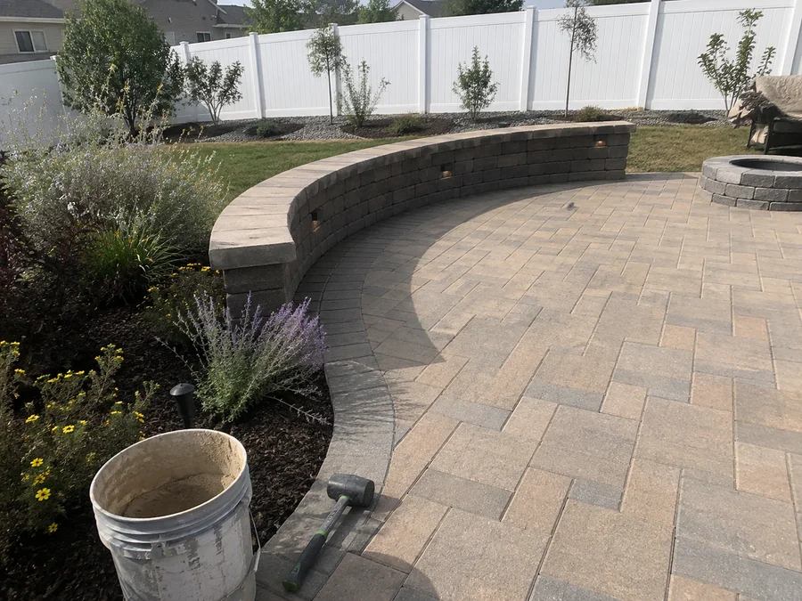 Back yard design combining a paver patio, seating wall and planted borders