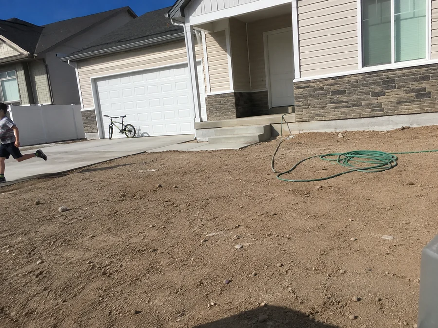 Bare compacted builder dirt at a new Utah home before landscaping begins