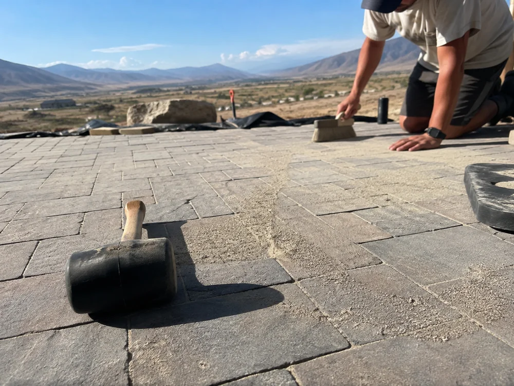 Interlocking concrete pavers being set with polymeric sand swept into the joints