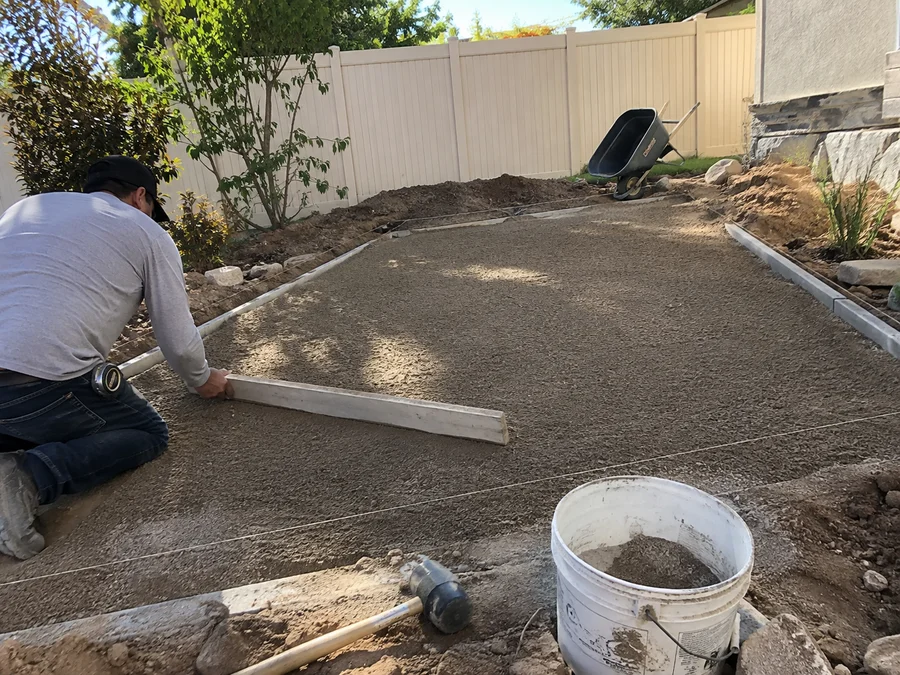 Compacted road base being screeded level for a new paver patio