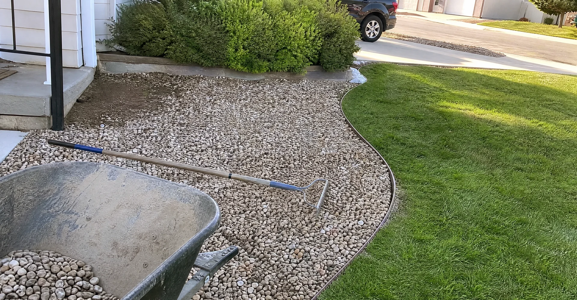 Decorative gravel bed with clean steel edging separating it from a green lawn in a Utah front yard