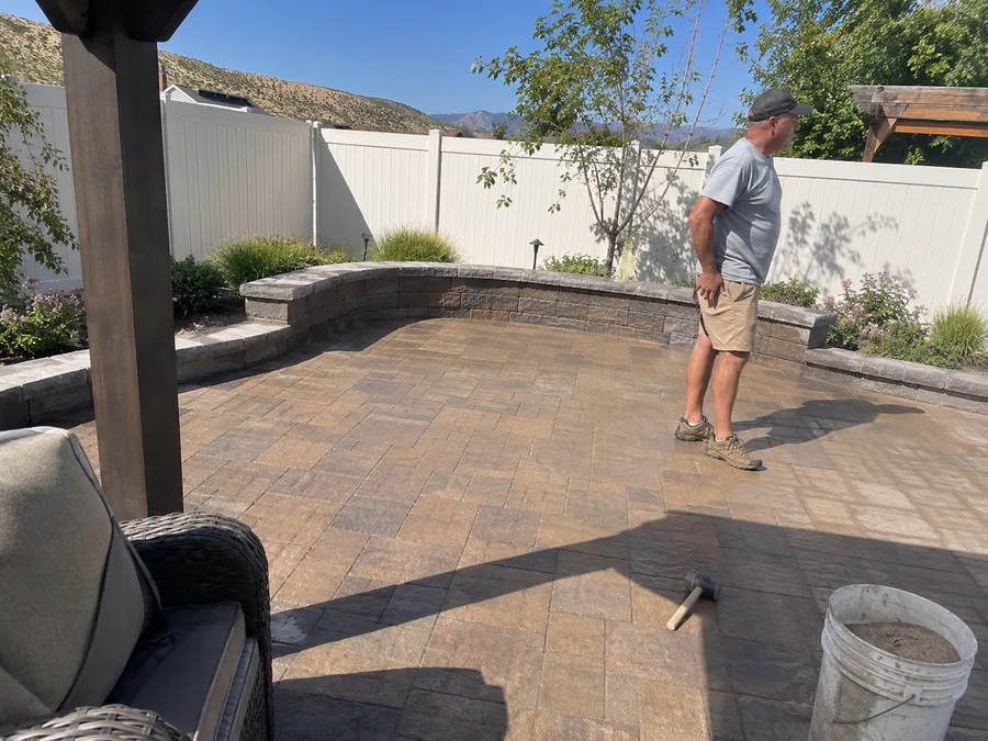 Finished paver patio with a low seating wall and planted borders