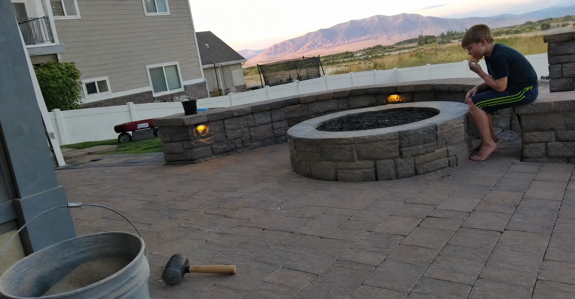 Paver patio with a stone fire pit and seating wall in a Utah back yard