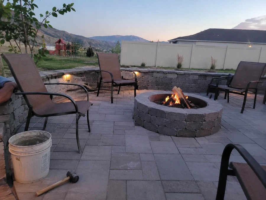 Stone fire pit with a surrounding paver seating area in a Tooele County back yard