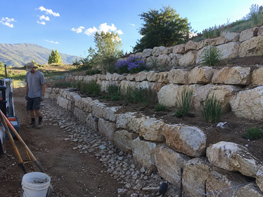Terraced boulder retaining walls stepping down a sloped rural Utah lot