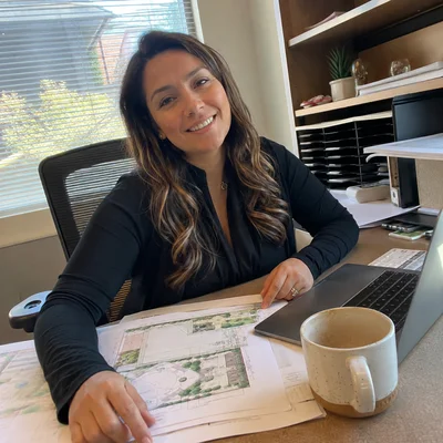 Viviana E., office manager at YLC Landscaping, reviewing landscape estimates at her desk